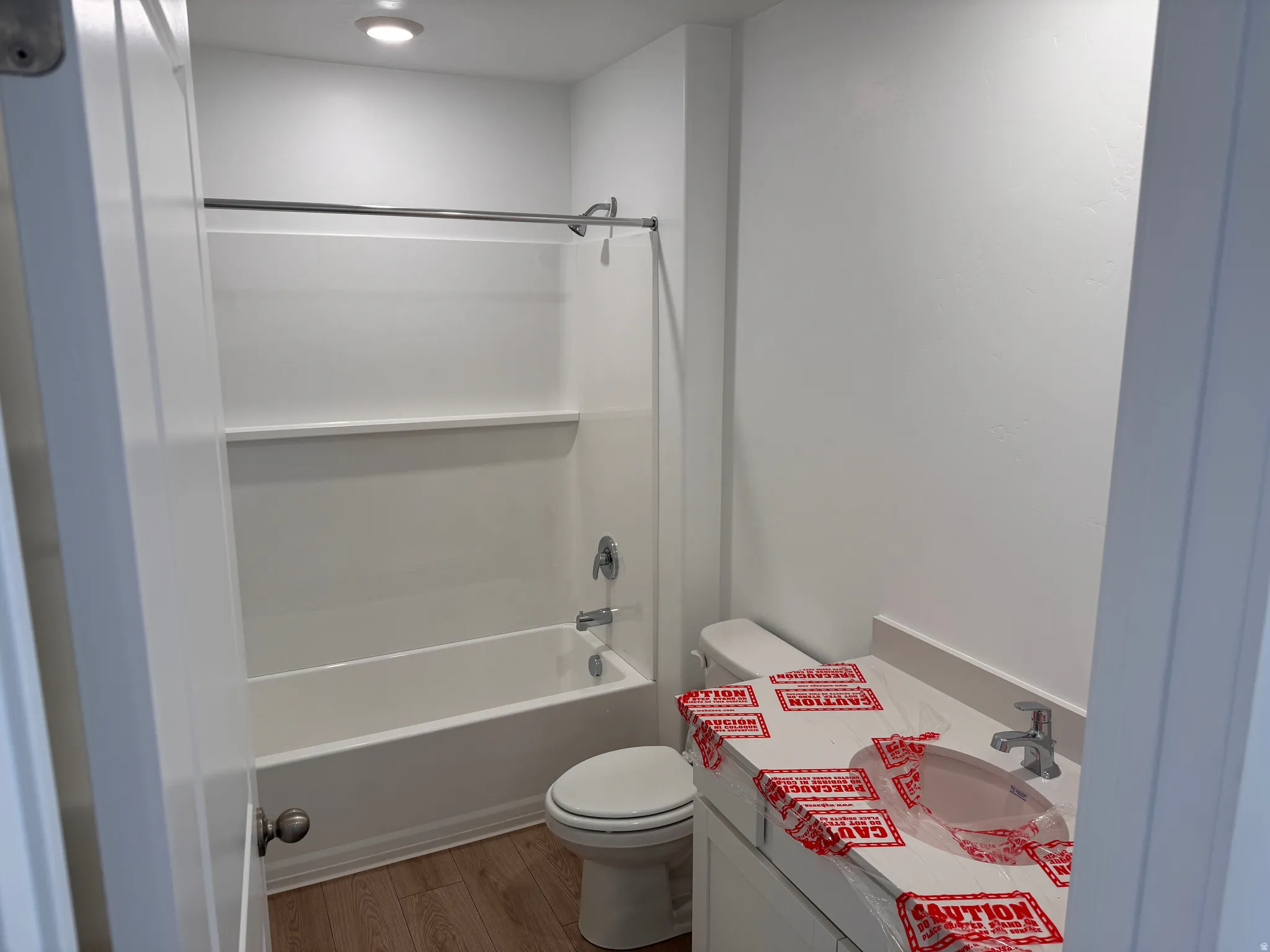 Bathroom featuring a white vanity with an integrated sink, chrome faucet, and wood-finish flooring