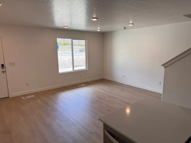 Open-concept living area featuring light wood-finish flooring, recessed ceiling lighting, and a neutral color palette