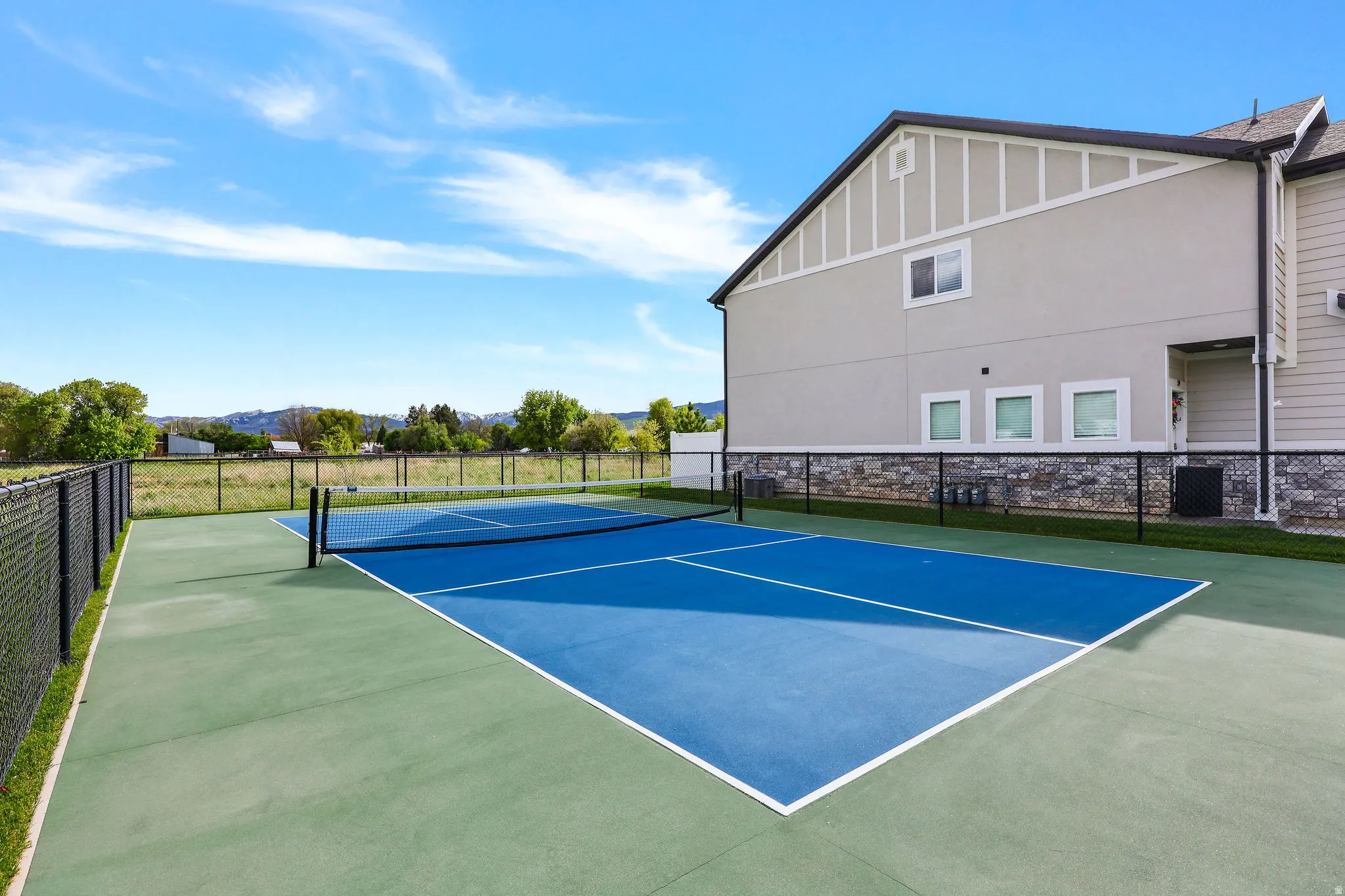 Outdoor court featuring a blue playing surface with white lines and a black net