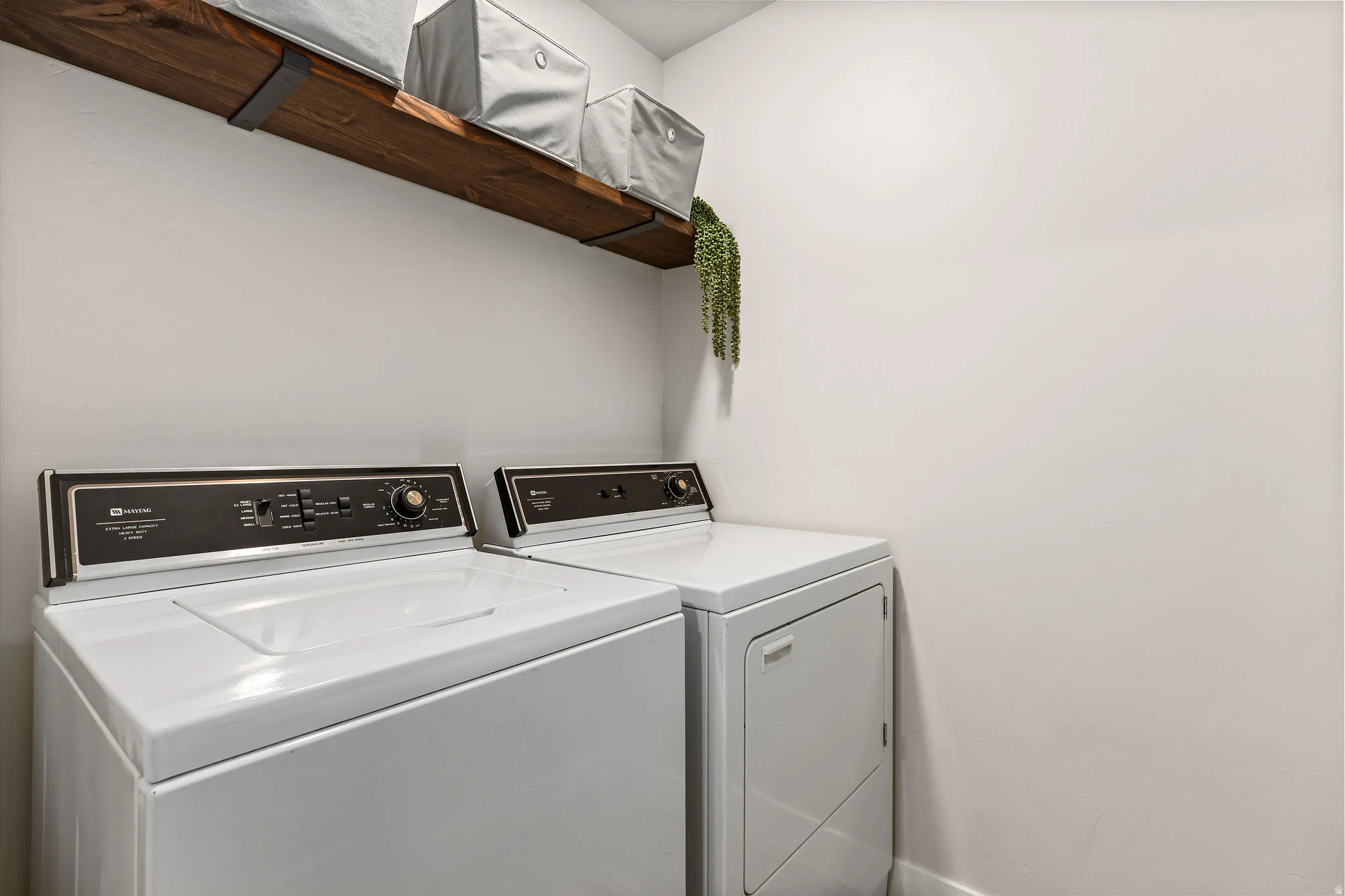 Dedicated laundry area featuring a wood-finish floating shelf with black metal brackets