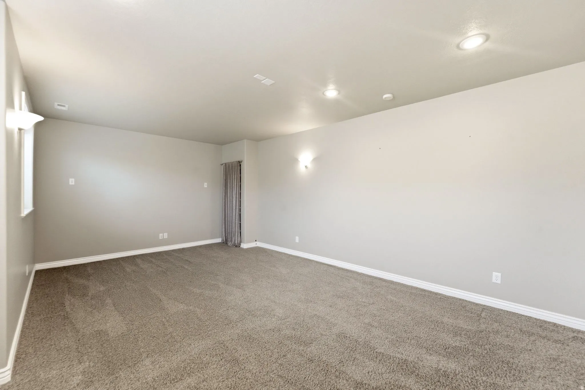 Spacious room featuring neutral carpeting and light gray walls