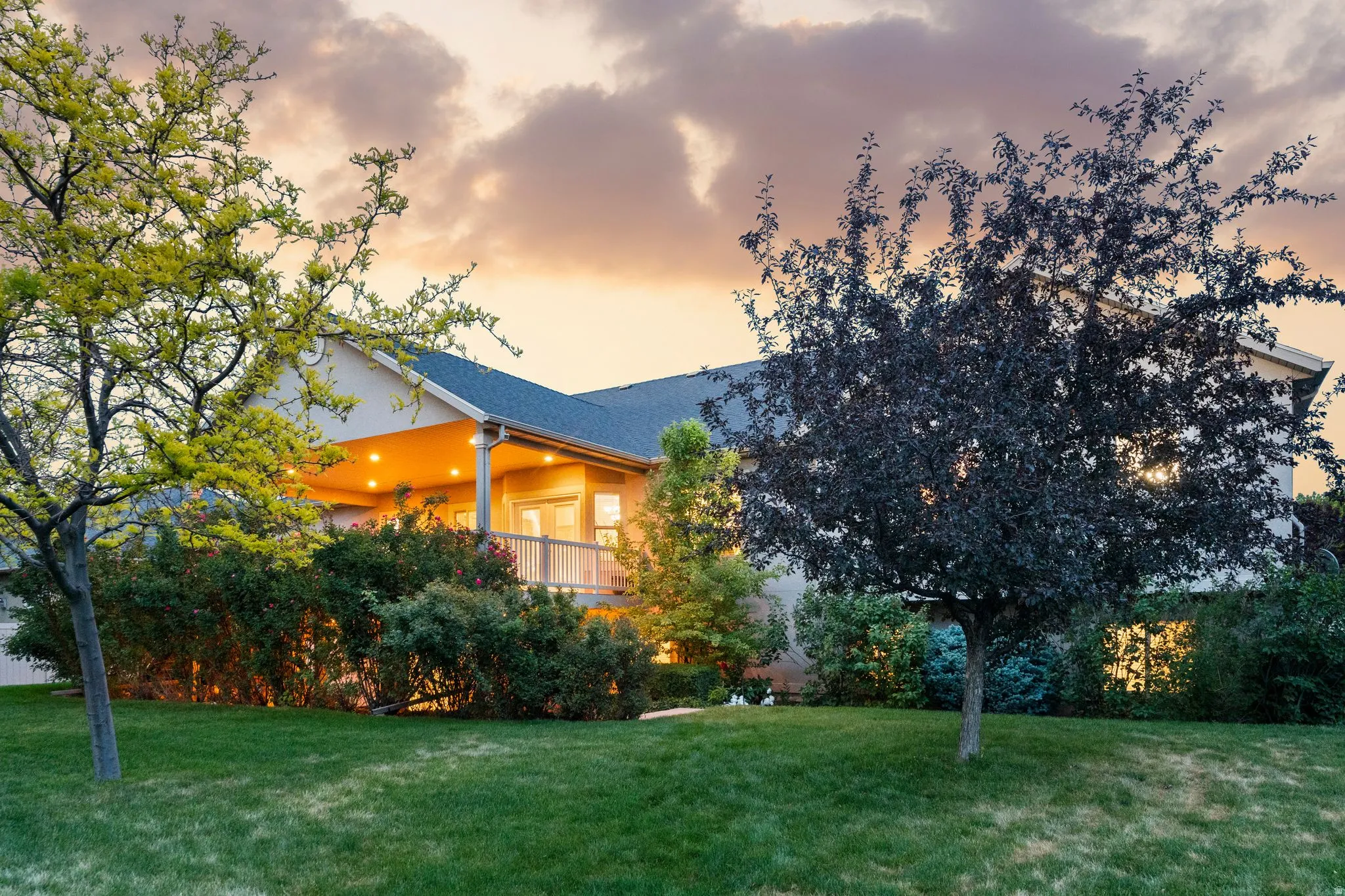 Expansive green lawn with mature trees fronting a stucco exterior