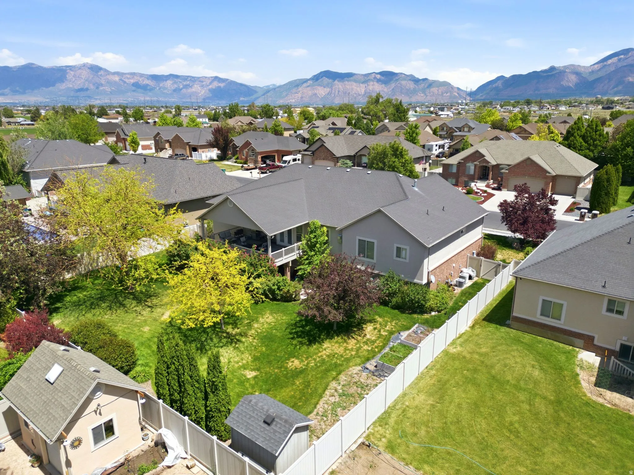 Expansive backyard featuring a manicured lawn, mature trees, and a mountain backdrop