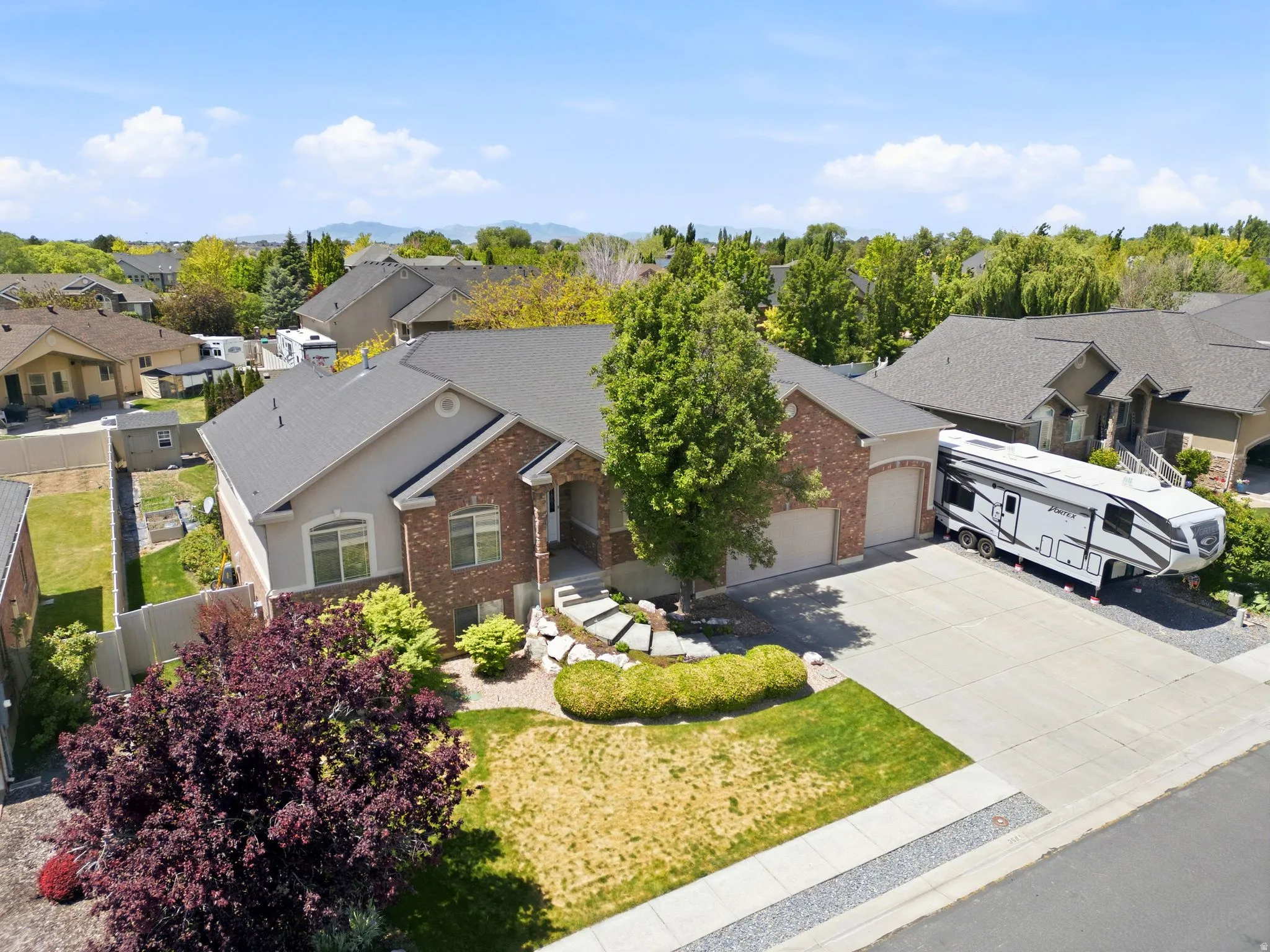Ranch-style exterior with brick and siding facade, a two-car garage, and an additional paved parking area