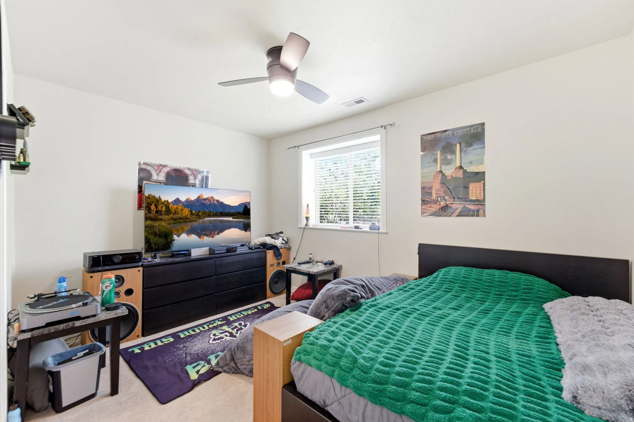 Carpeted room with a ceiling fan, white walls, and a window with blinds
