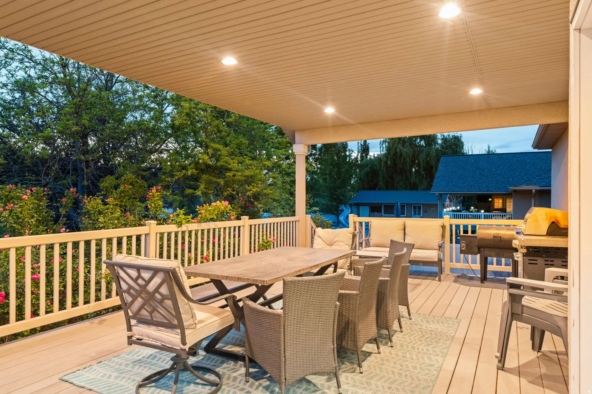 Covered outdoor deck featuring composite decking, recessed lighting, and a white balustrade railing