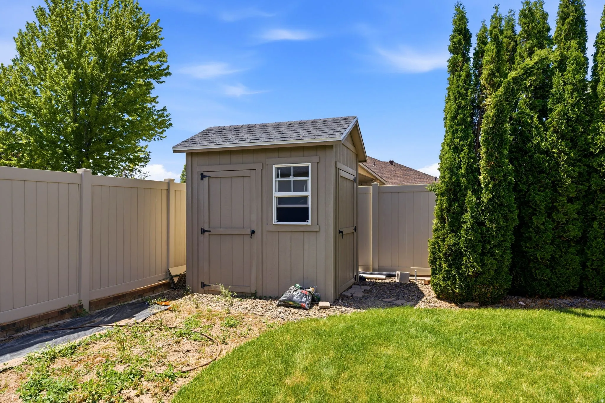 Outdoor storage shed featuring a single window and double doors