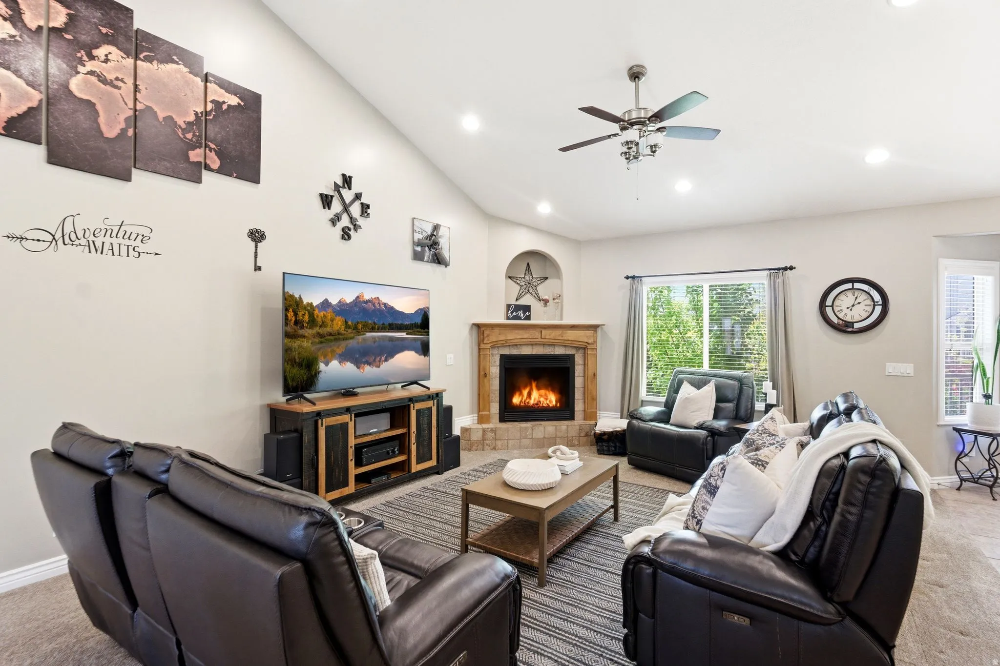Vaulted ceiling living area featuring a fireplace with a wood-finish mantel and stone surround, recessed lighting, and a ceiling fan