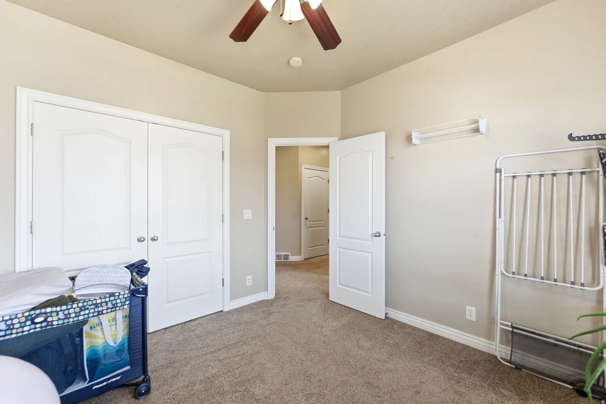 Carpeted room featuring a ceiling fan, dual white panel doors, and neutral wall paint