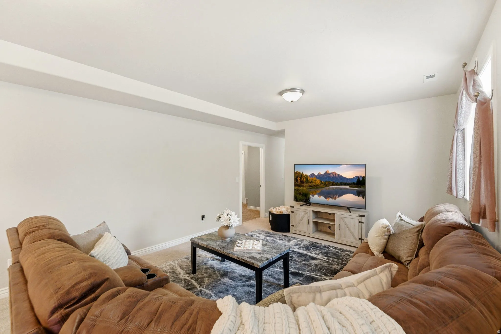 Spacious living area featuring light-colored walls and crown molding
