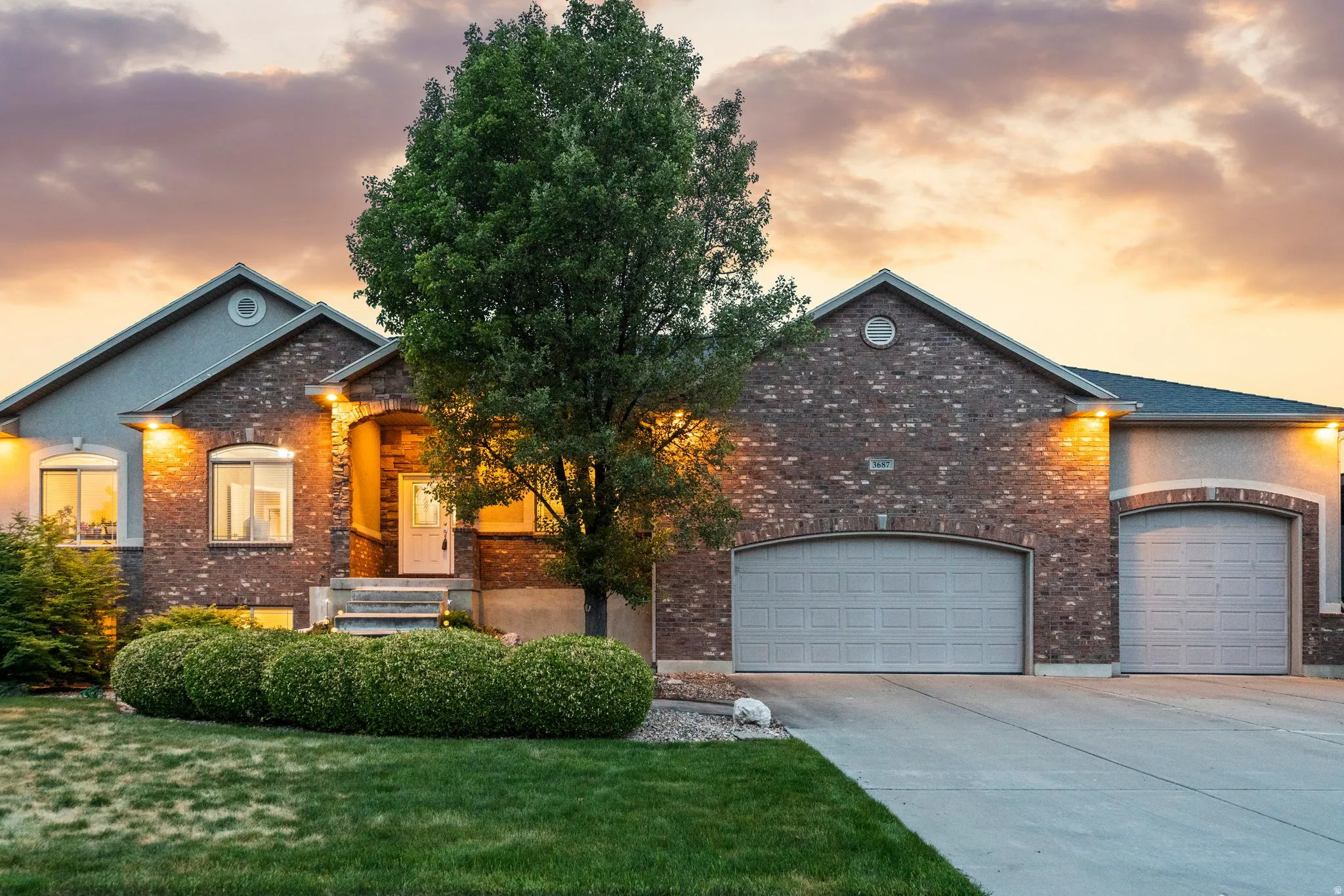 Brick exterior featuring a covered entry, arched windows, and a multi-car driveway