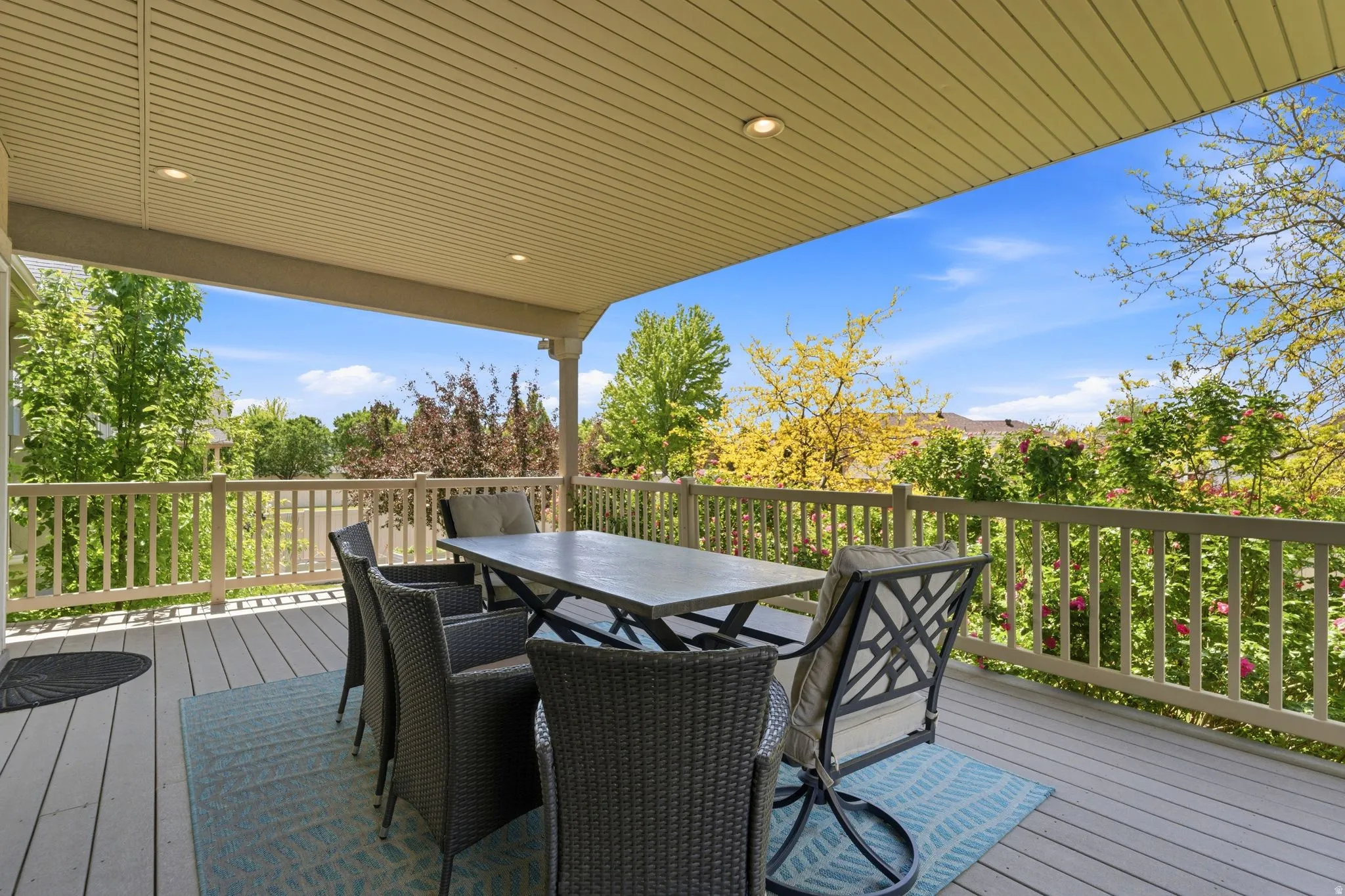 Covered outdoor deck featuring composite decking, recessed lighting, and a white railing system