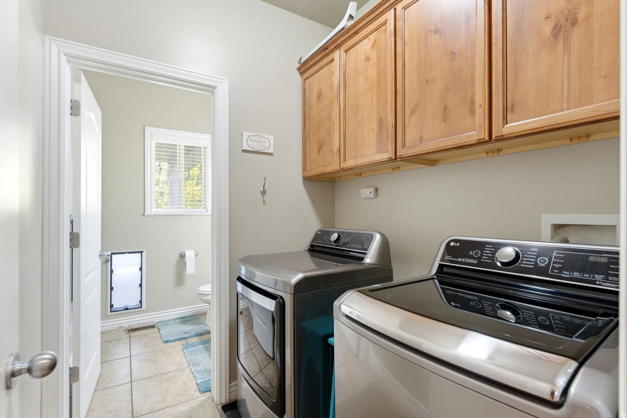 Dedicated laundry area featuring upper wood cabinetry and light neutral wall paint