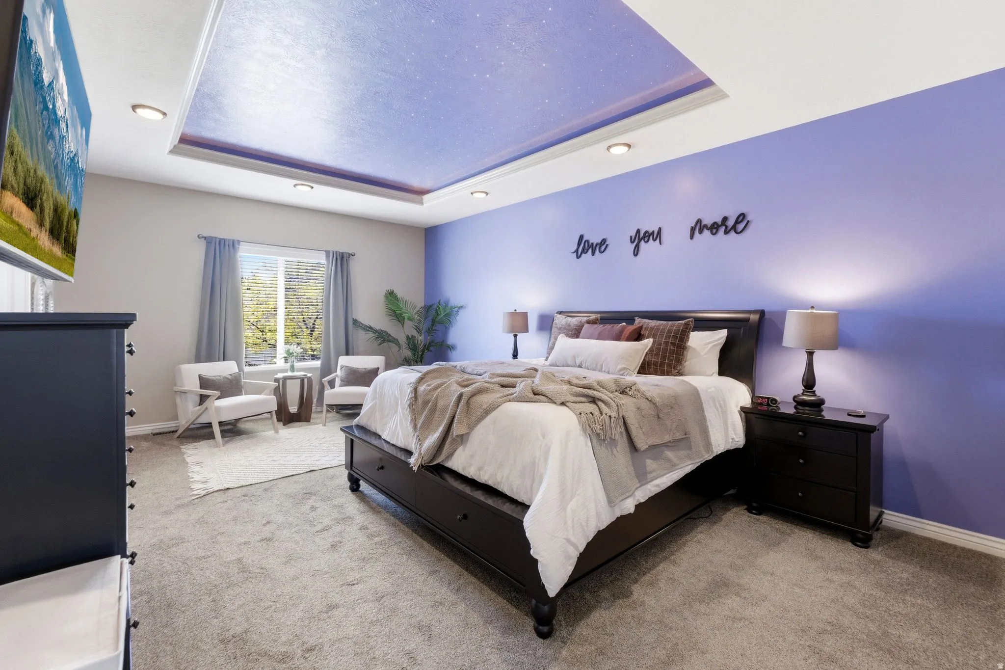 Recessed tray ceiling with integrated lighting, wall-mounted television, and light gray wall-to-wall carpeting