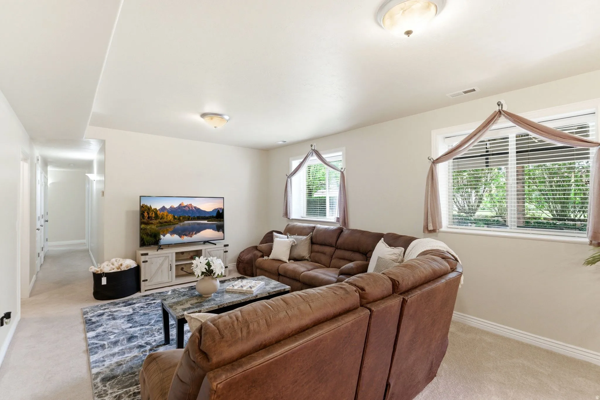 Spacious living area featuring light-colored walls and plush carpeting