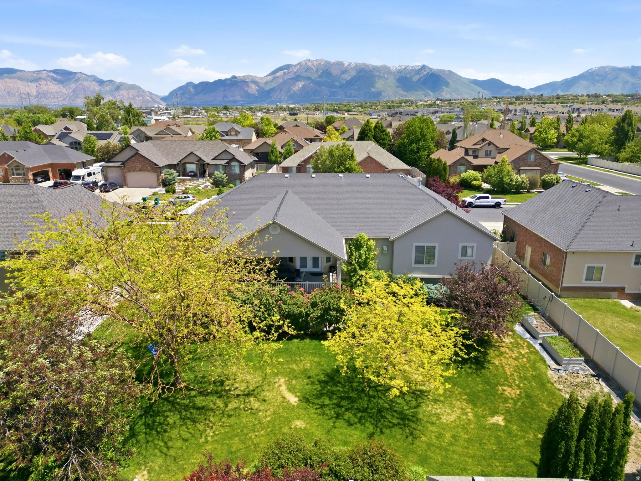 Expansive property featuring a sizable backyard with mature trees, manicured lawn, and raised garden beds