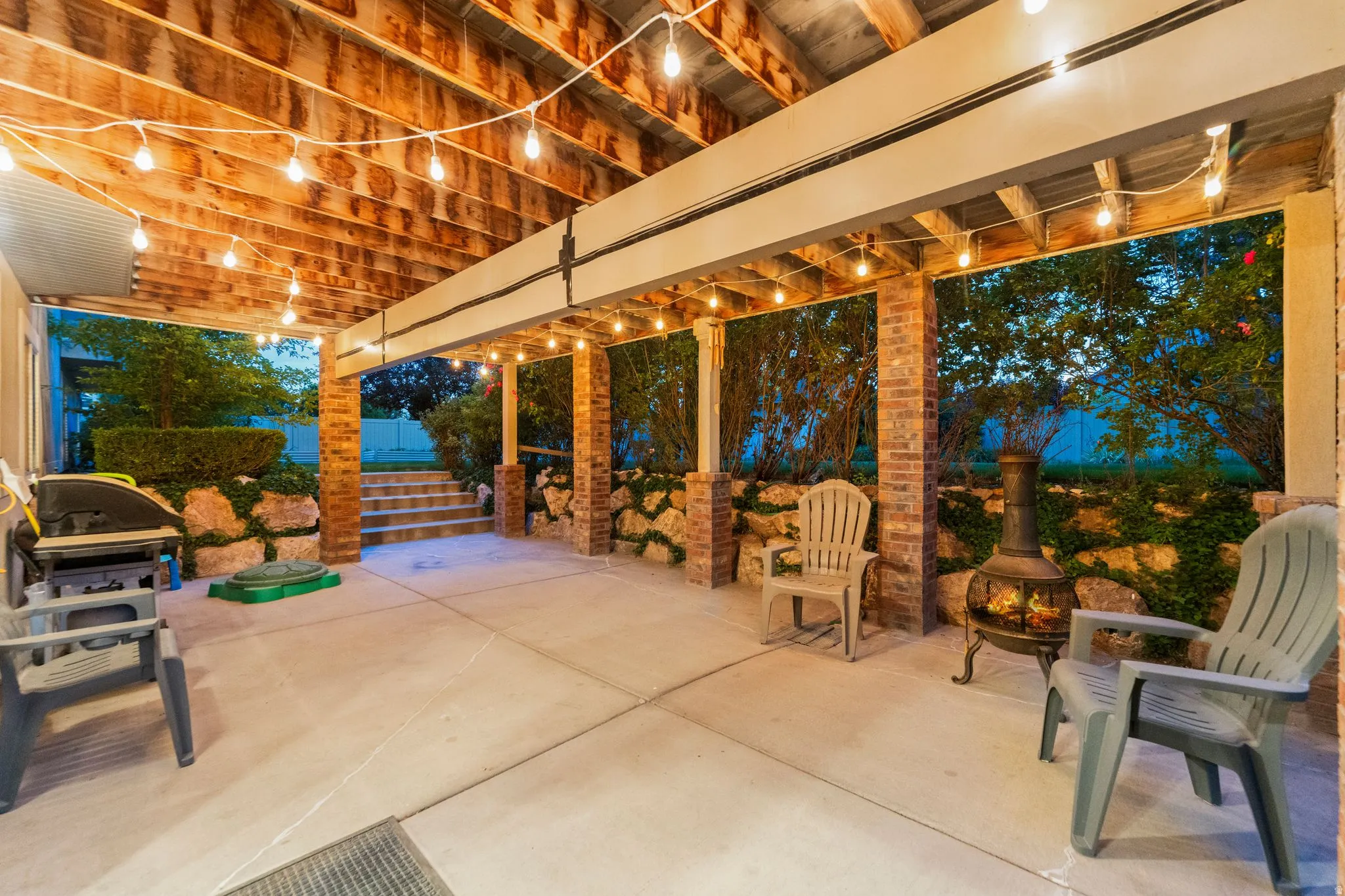 Covered patio featuring string lights, concrete flooring, and exposed wood ceiling