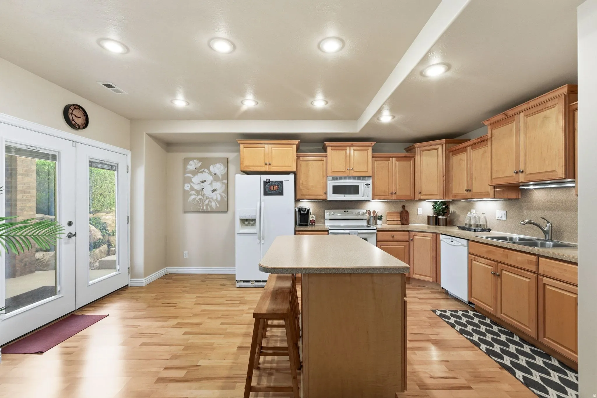 Kitchen featuring light wood-finish cabinetry, a central island with bar seating, and stainless steel appliances