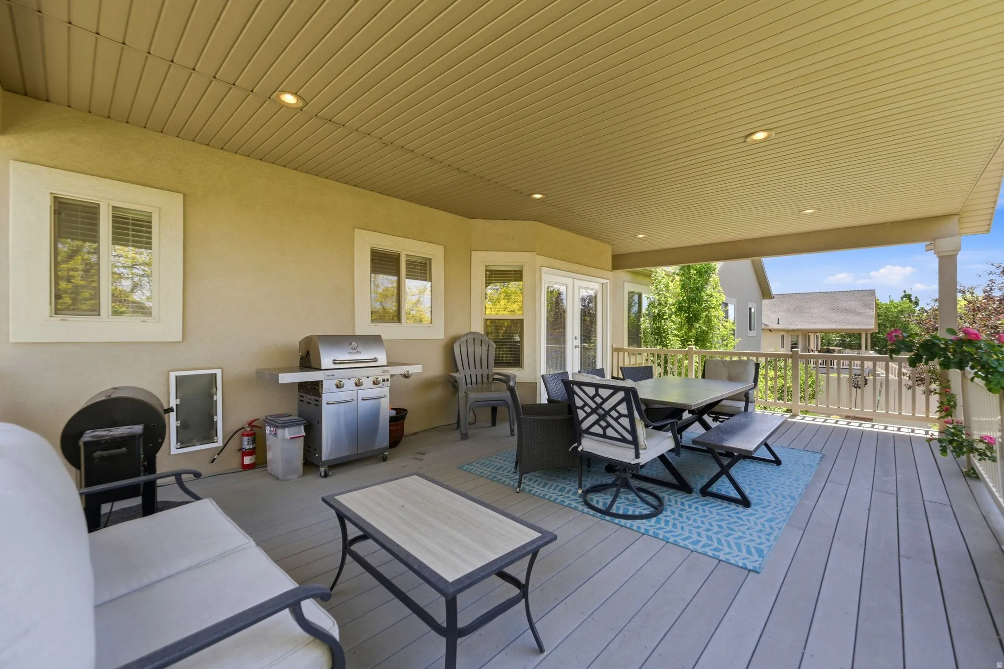Expansive covered deck featuring composite decking, recessed lighting, white perimeter railing, and exterior stucco siding