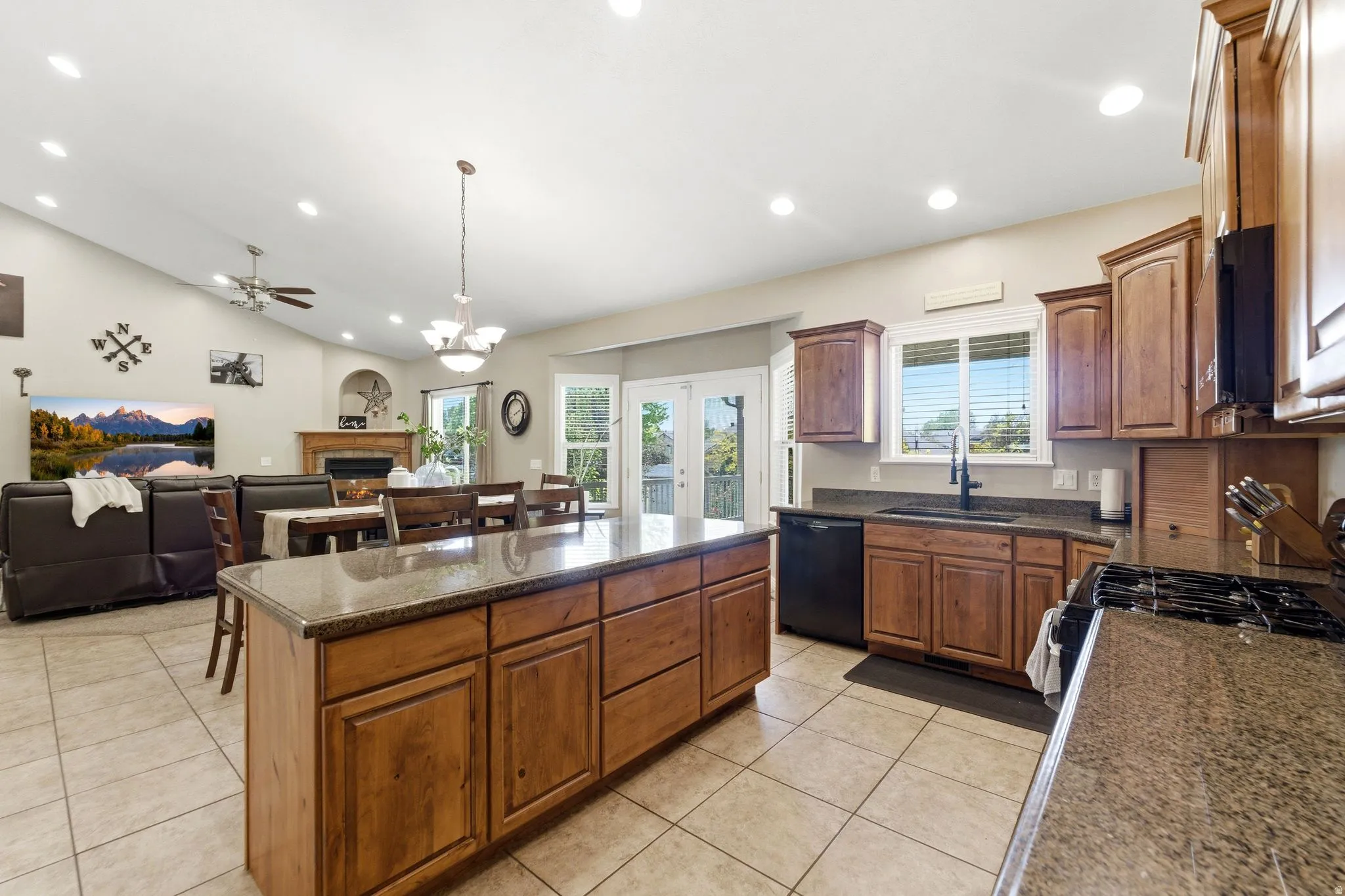 Spacious kitchen featuring a large island with stone countertops, wood cabinetry, and tile flooring