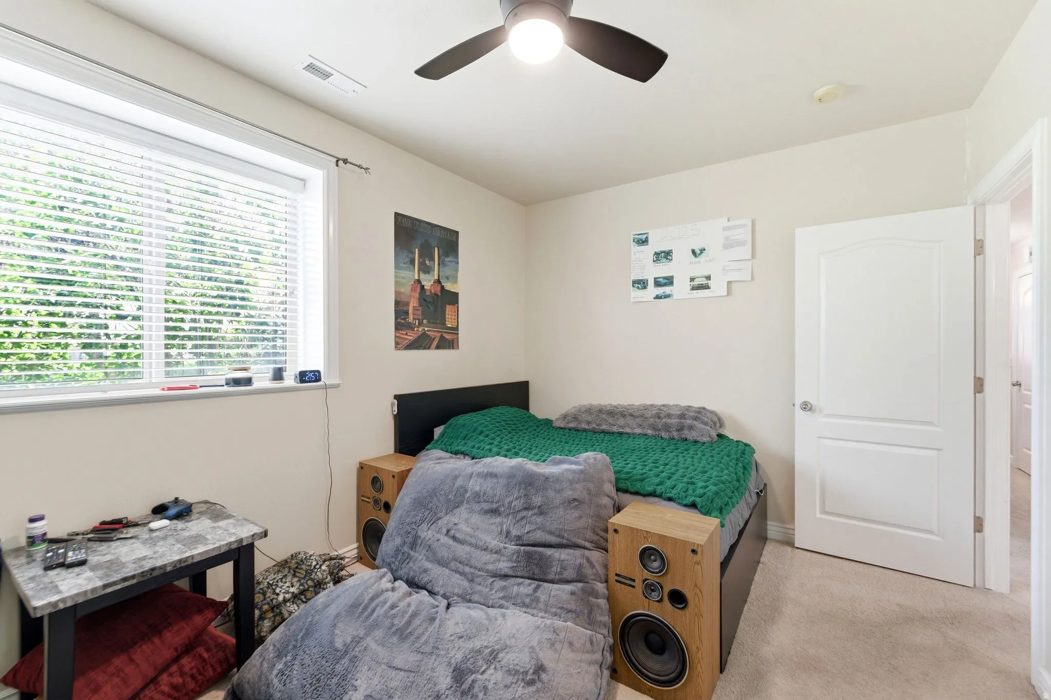Bedroom with a ceiling fan, a window with horizontal blinds, neutral wall paint, and carpeting