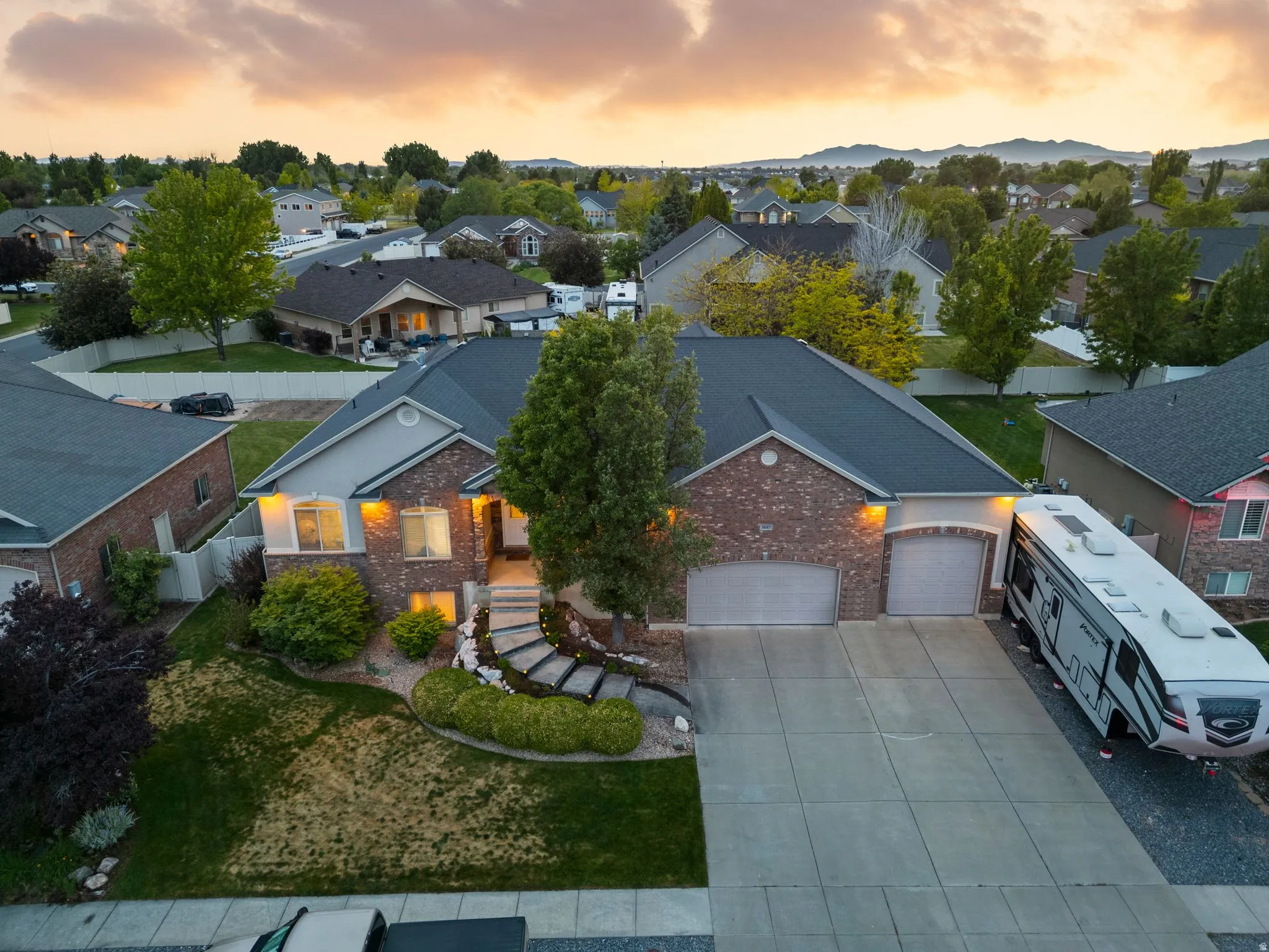 Brick and stucco exterior featuring a tiered stone pathway, a two-car garage, and mature landscaping