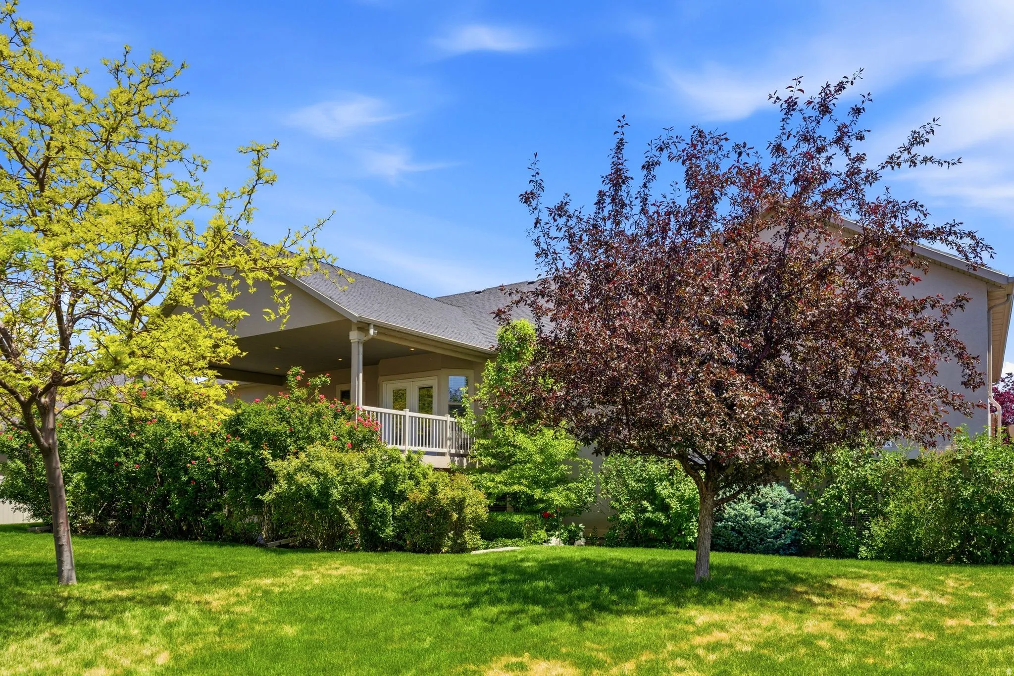 Rear exterior featuring a covered porch with white railing, double patio doors, and a shingled roof
