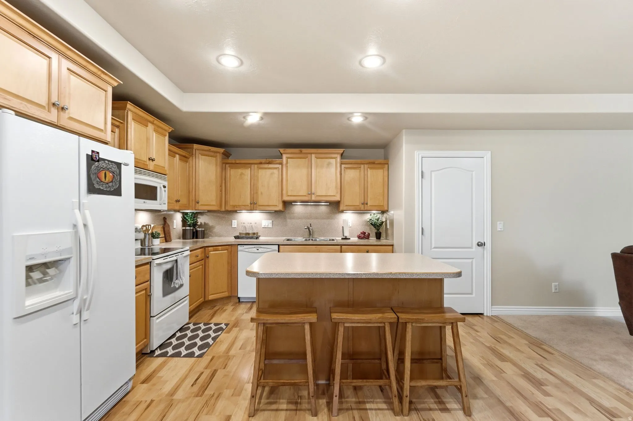 Kitchen featuring light wood-finish cabinetry, a central island with bar seating, and wood-finish flooring