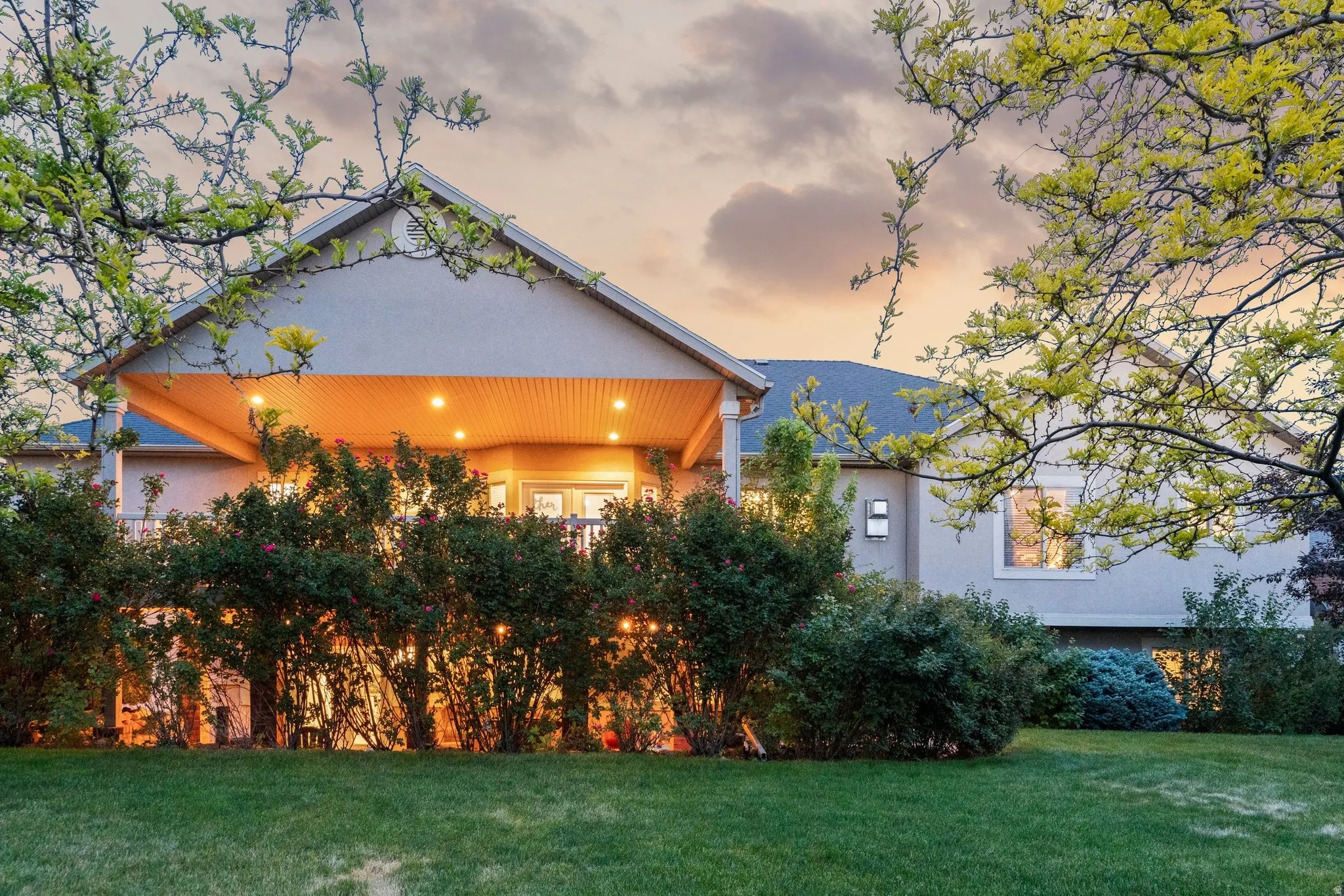 Expansive backyard featuring a manicured lawn, established shrubbery, and mature trees