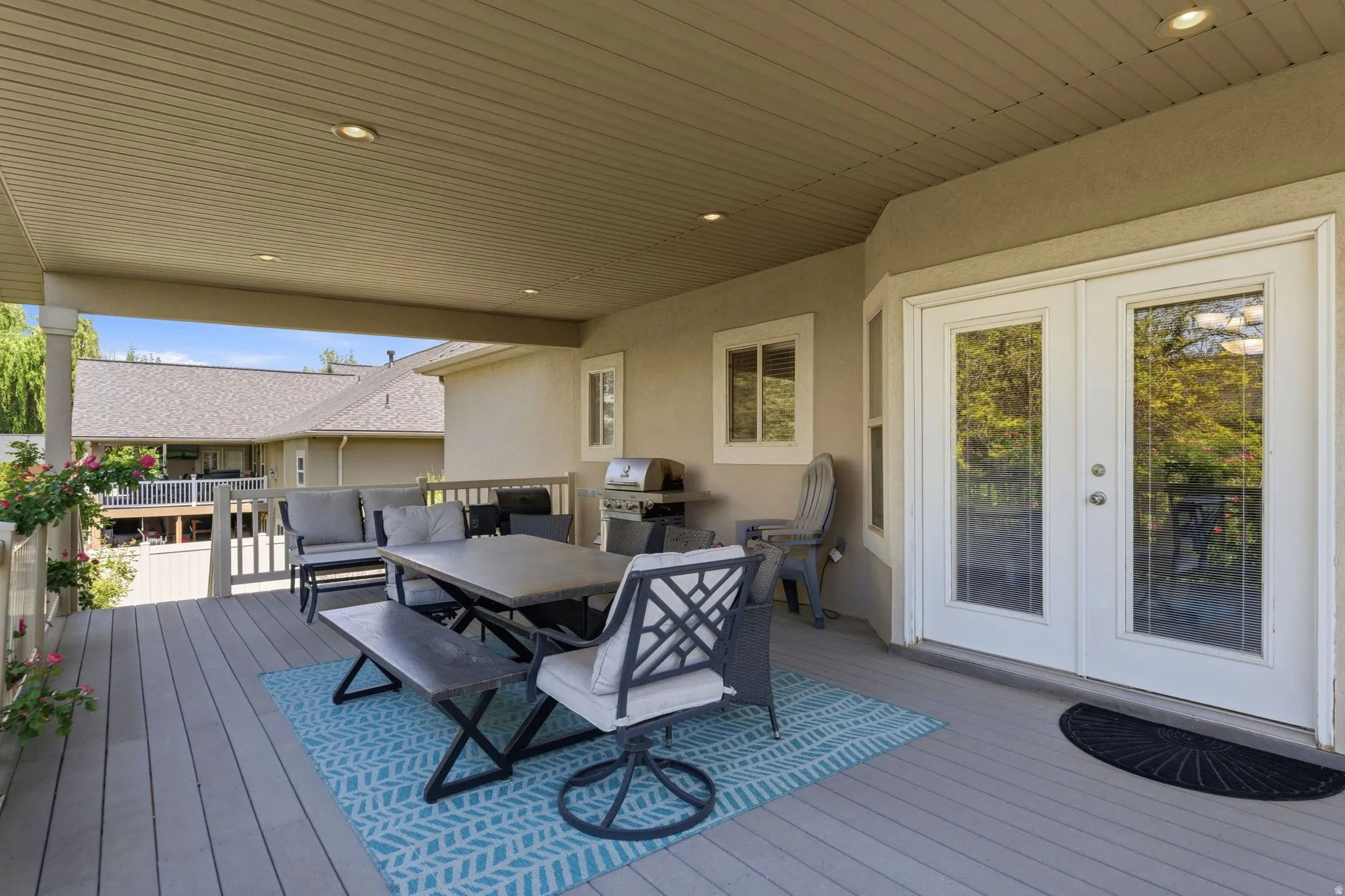 Spacious covered deck featuring composite decking, recessed lighting, and a white railing system