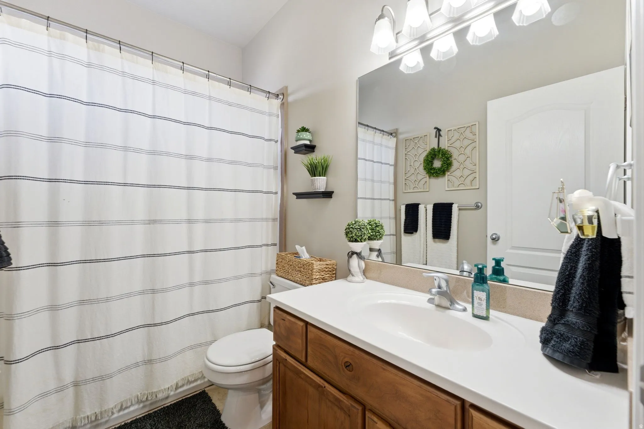 Bathroom featuring a single vanity with wood-finish cabinetry, a white countertop, and an undermount sink