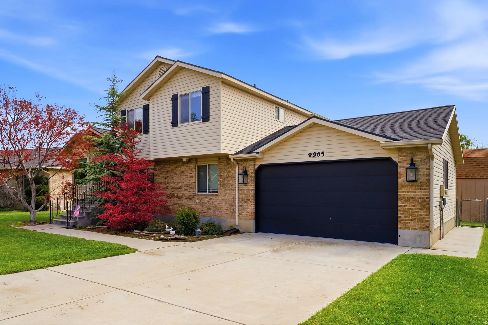 Exterior featuring beige siding and brick accents, a two-car garage with a dark door, and a concrete driveway