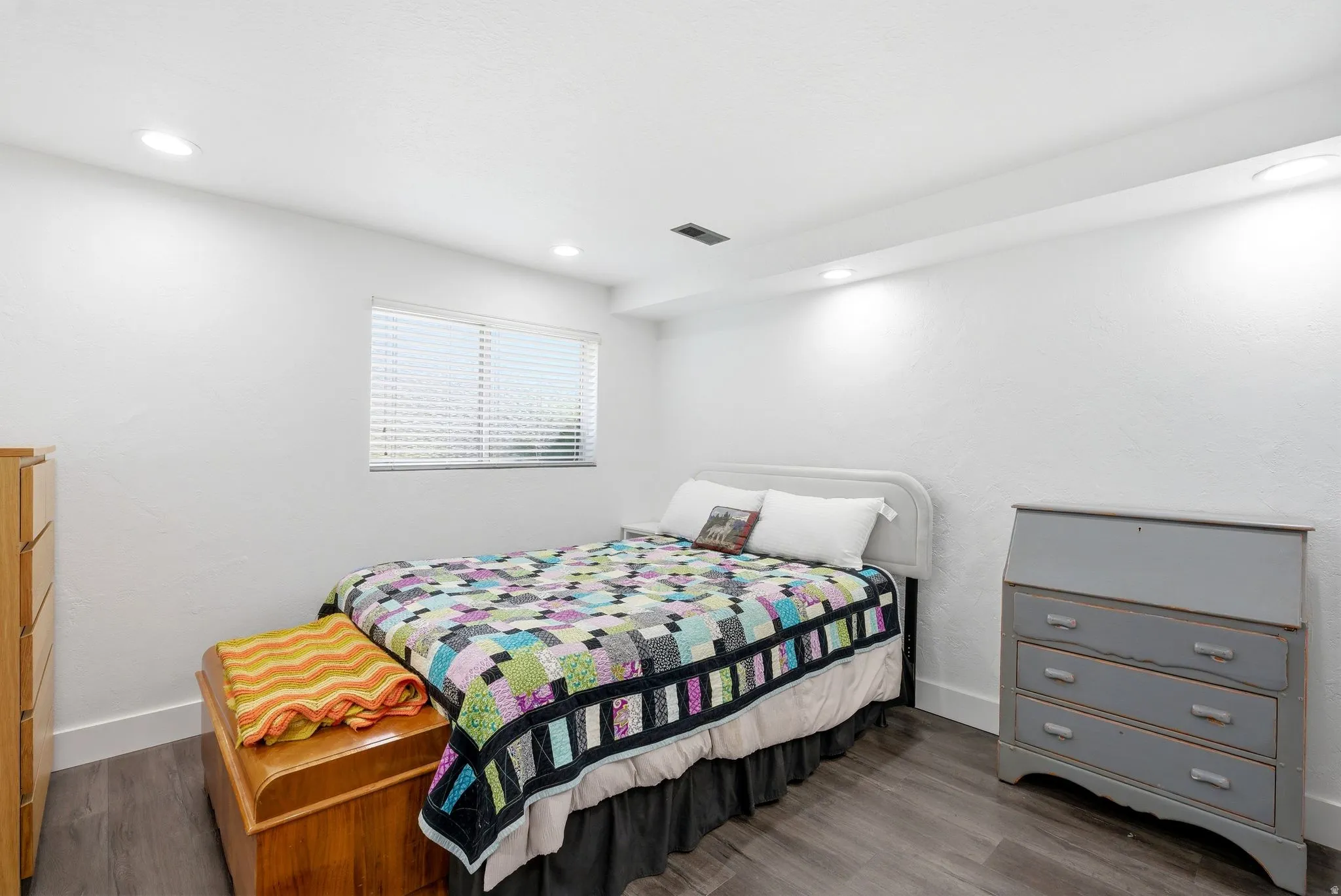 White walls with textured finish, recessed lighting, and wood-finish flooring