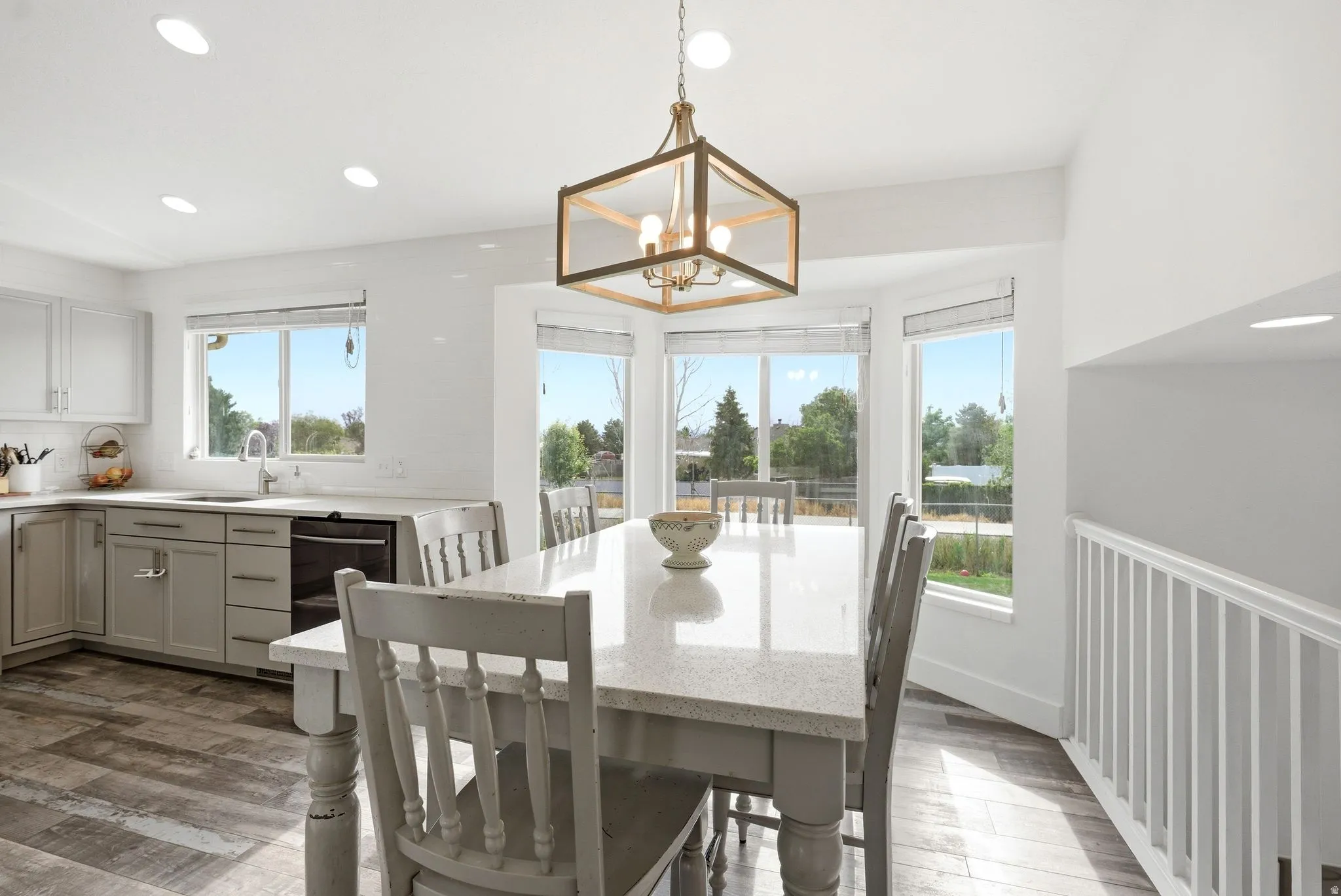 Open-concept dining area featuring a bay window, wood-finish flooring, and a contemporary chandelier