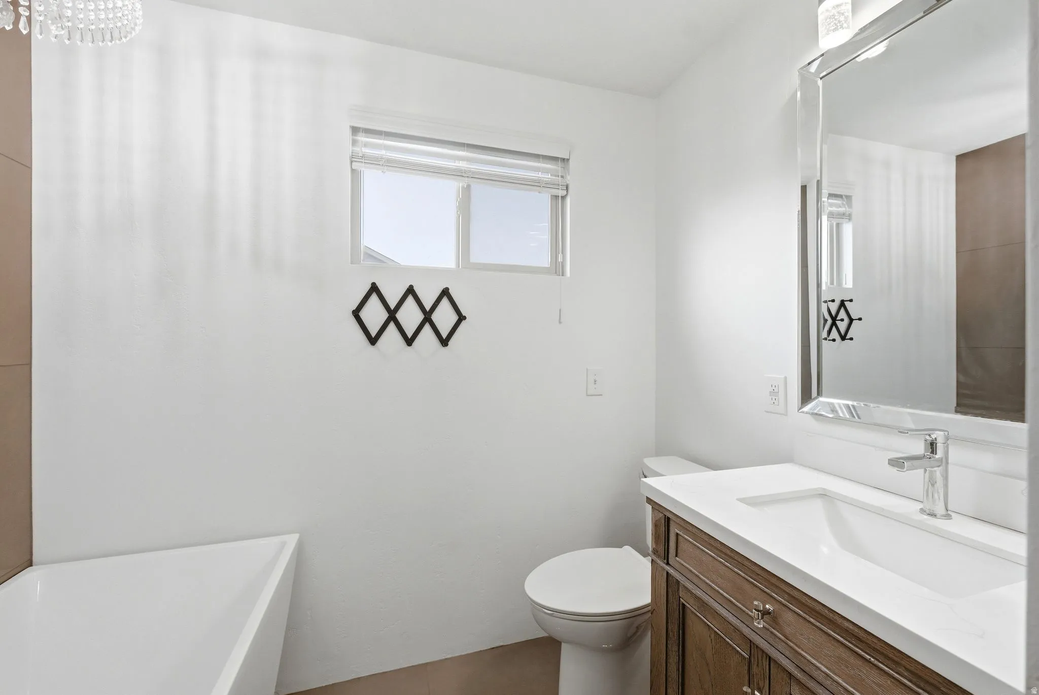 Bathroom featuring a vanity with wood-finish cabinetry, a single basin sink, and a chrome faucet