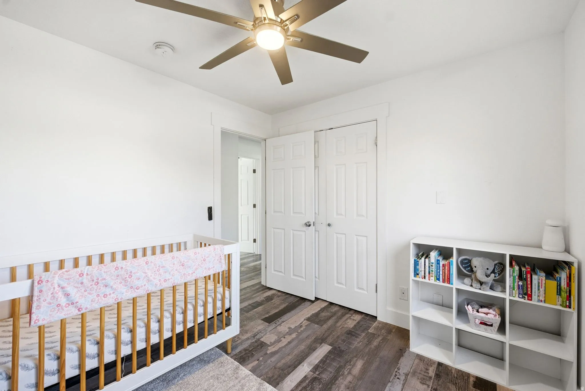 Room with wood-finish flooring, white walls, and a ceiling fan with integrated lighting