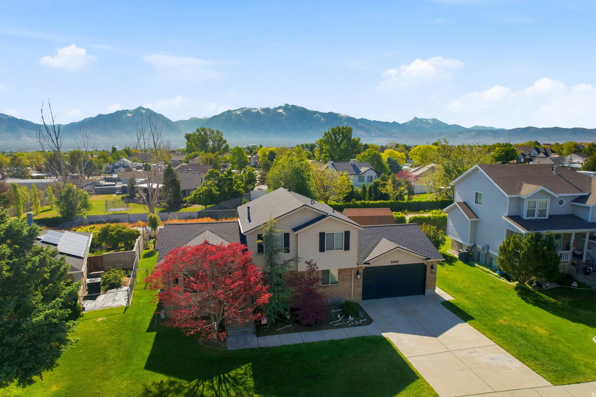 Two-story residence featuring a two-car garage, concrete driveway, and mature landscaping