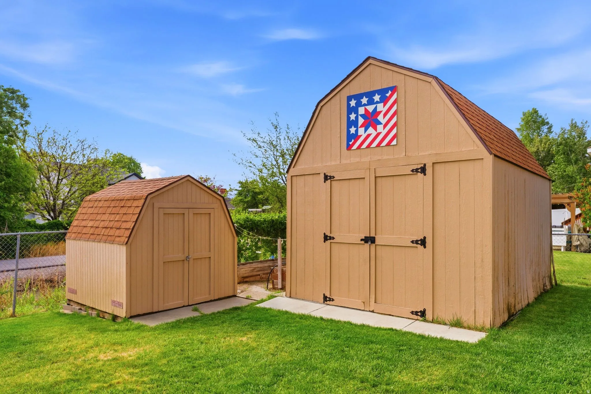 Two storage sheds with gambrel roofs and wood panel siding