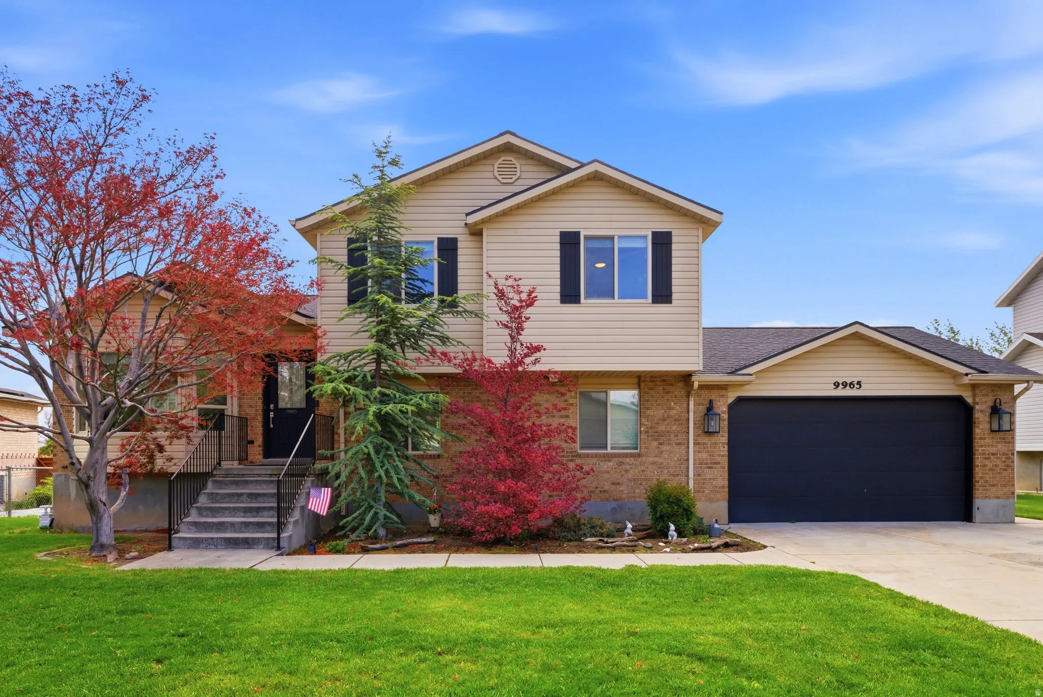 Two-story residence featuring a brick and siding exterior, an attached two-car garage with a dark door, and concrete driveway