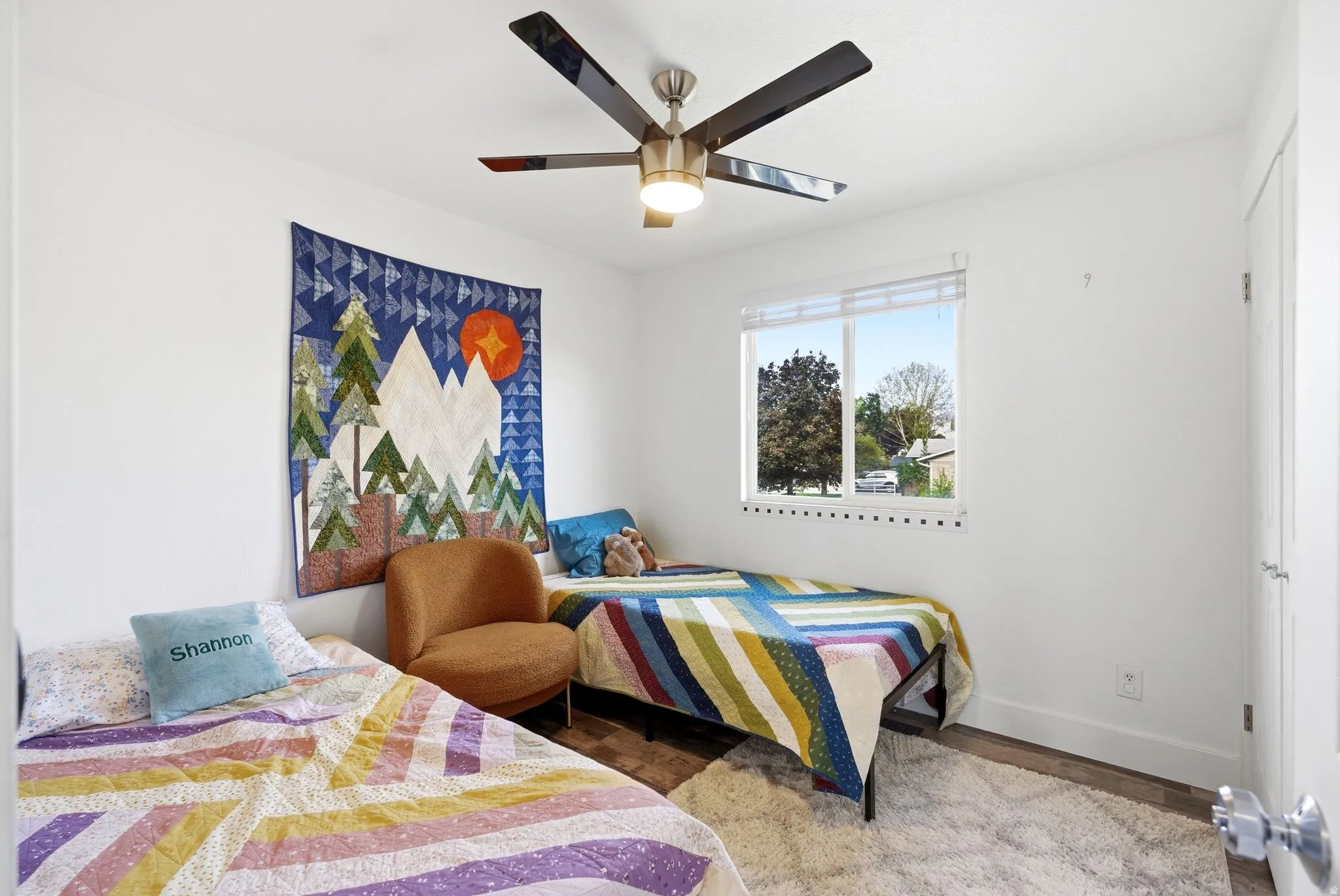 Bright room with a modern ceiling fan featuring a light fixture, a window with blinds, and wood-finish flooring