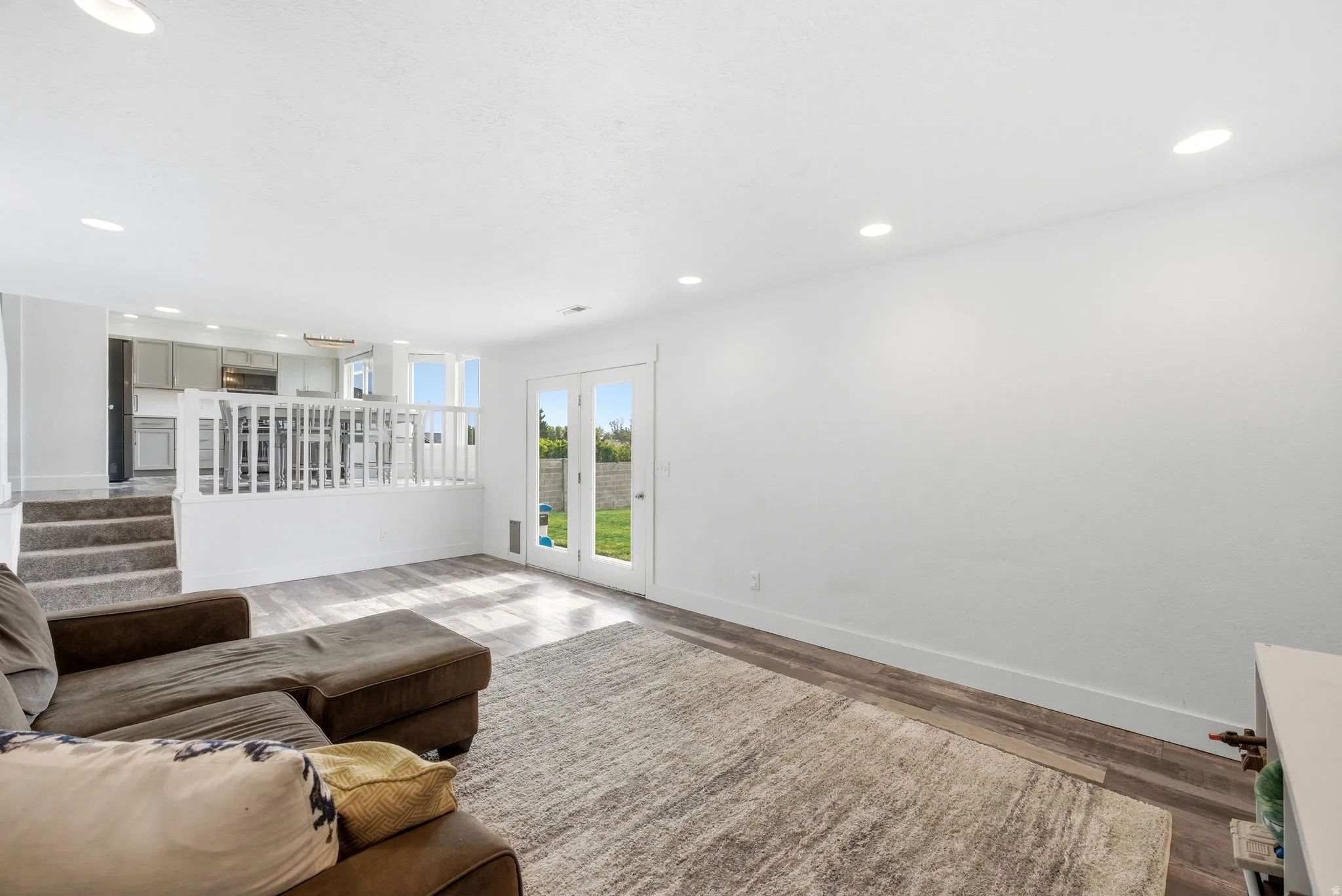 Open-concept living space featuring wood-finish flooring, recessed lighting, and white walls