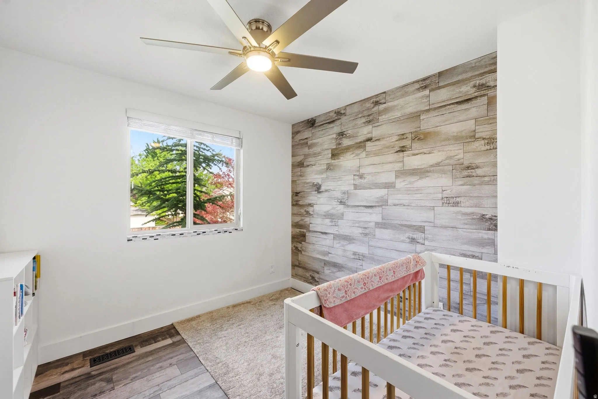 Room featuring a wood-finish accent wall and a window with blinds