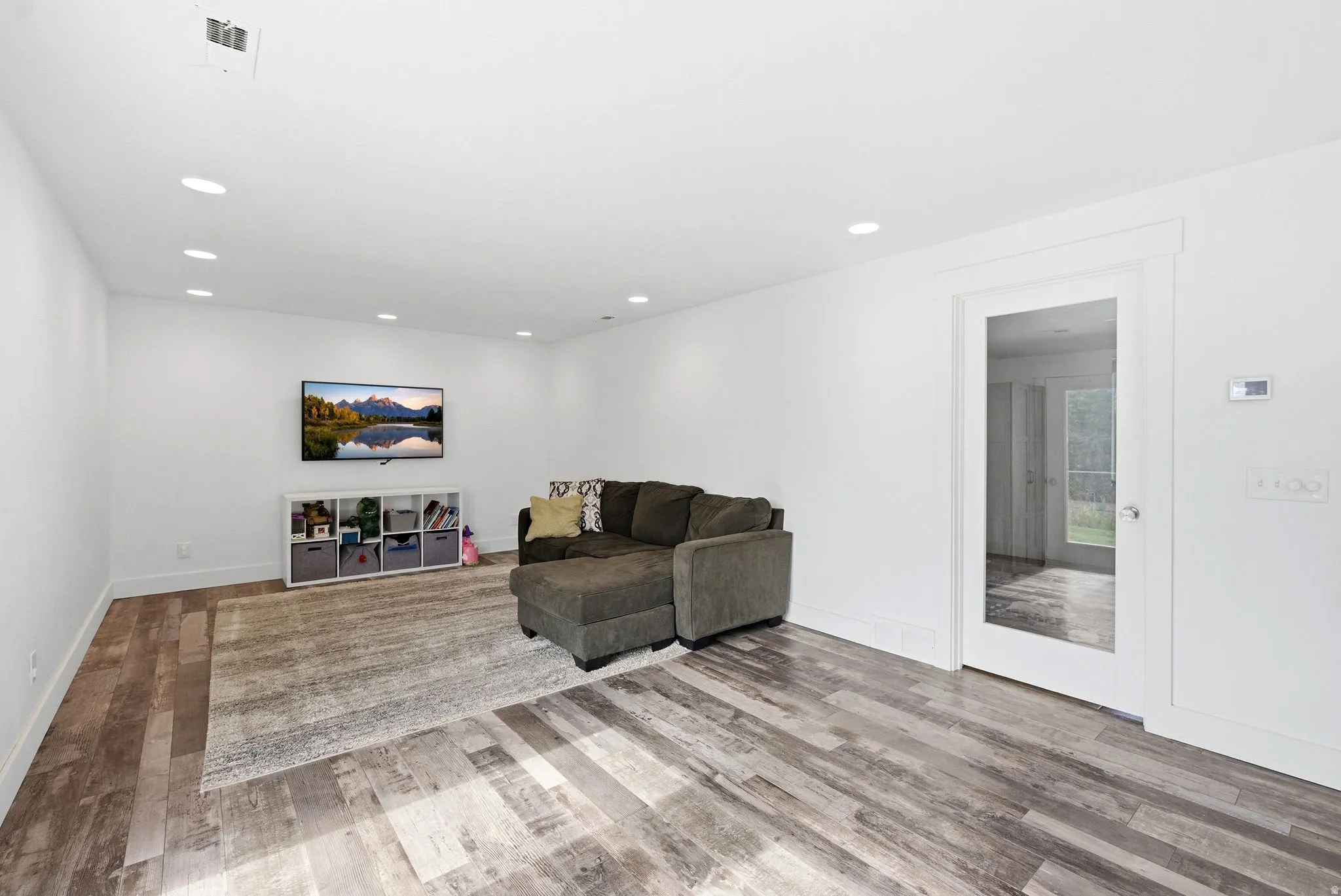 Spacious room featuring wood-finish flooring, recessed lighting, and white baseboards