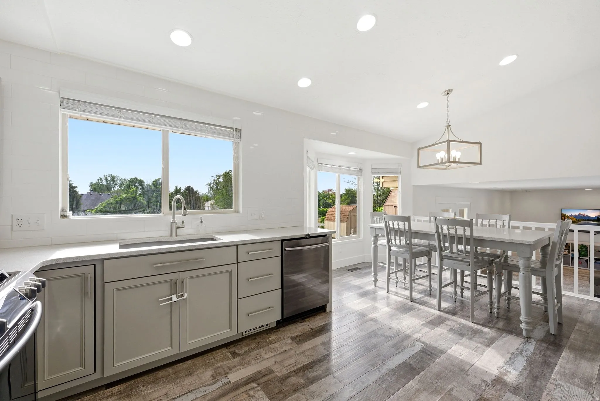 Kitchen featuring light gray cabinetry, stainless steel sink, subway tile backsplash, and quartz countertops