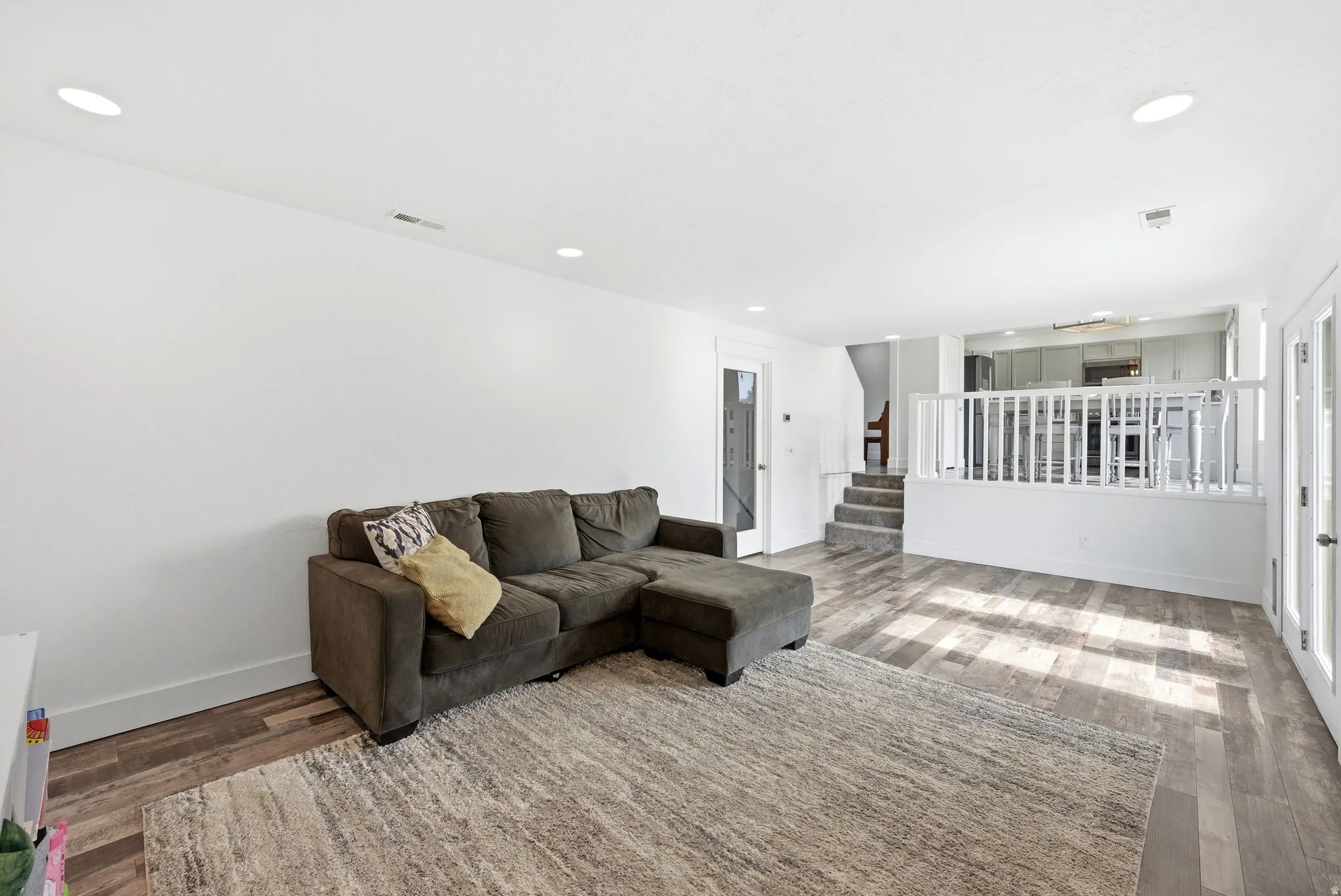 Open-concept living area featuring wood-finish flooring, recessed lighting, and white baseboards