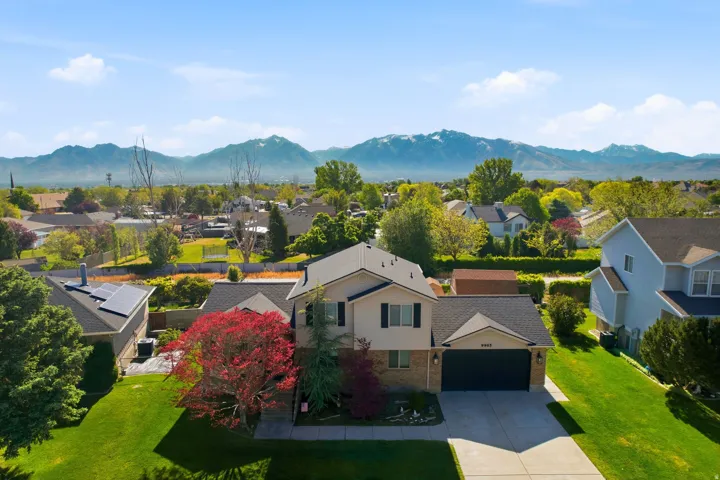 Two-story residence featuring a two-car garage, manicured front lawn, and mature landscaping