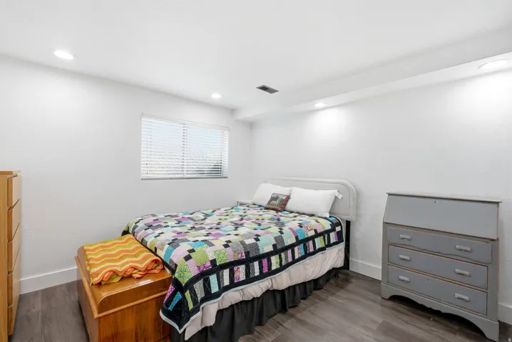 White walls with textured finish, recessed lighting, and wood-finish flooring