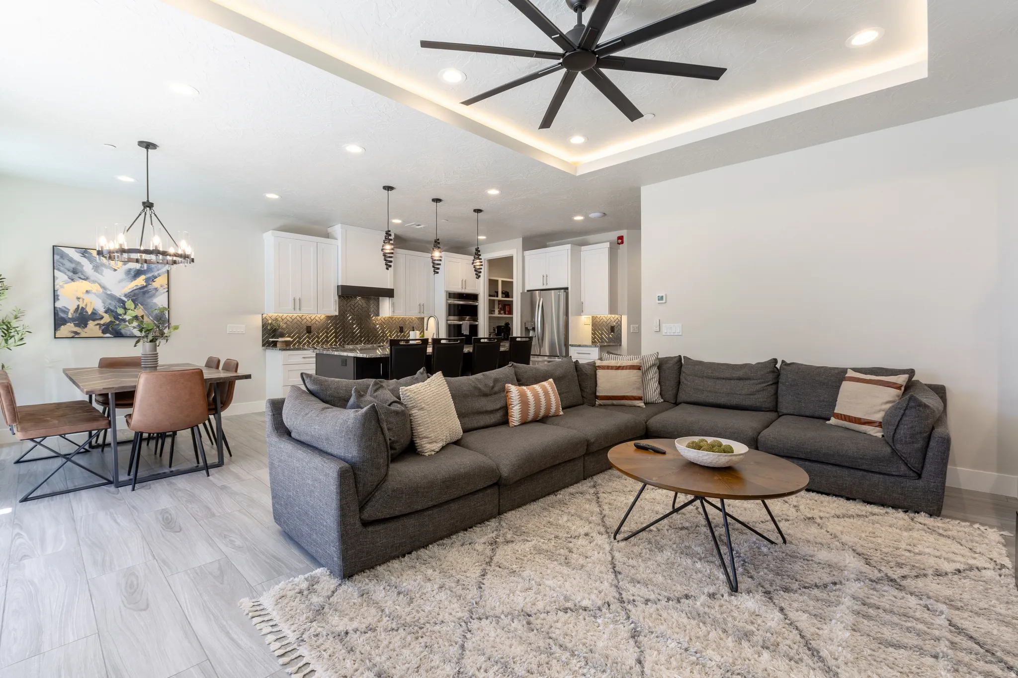 Open-concept living area featuring light wood-finish flooring, a contemporary ceiling fan with integrated lighting, and recessed ceiling lights