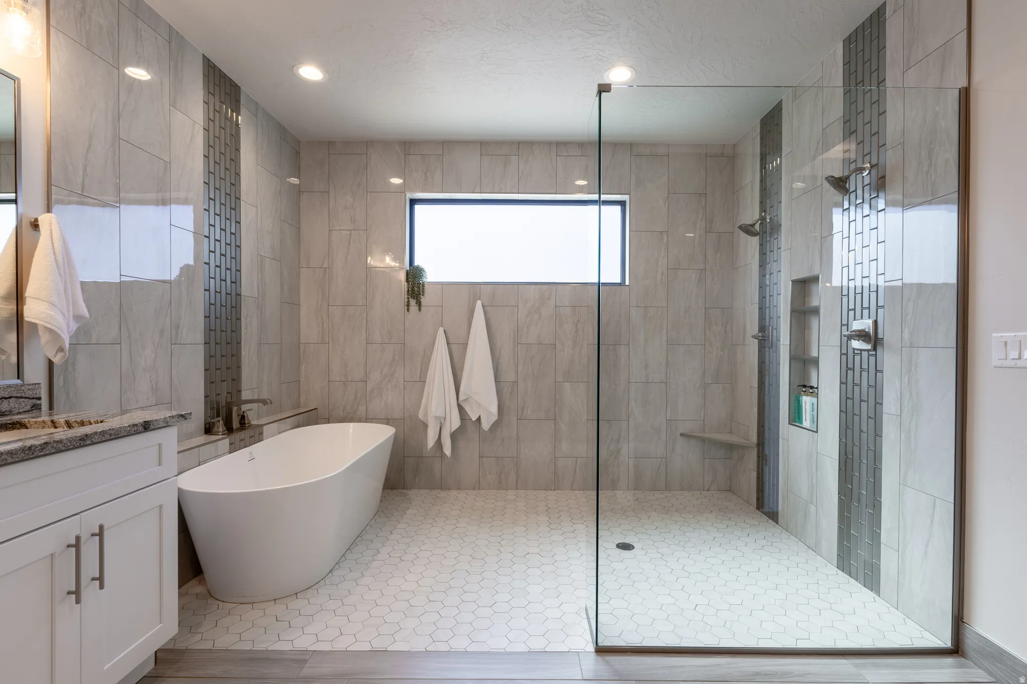 Modern bathroom featuring a freestanding soaking tub, a spacious glass-enclosed shower with dual shower heads, a built-in shower niche, and an integrated shower bench