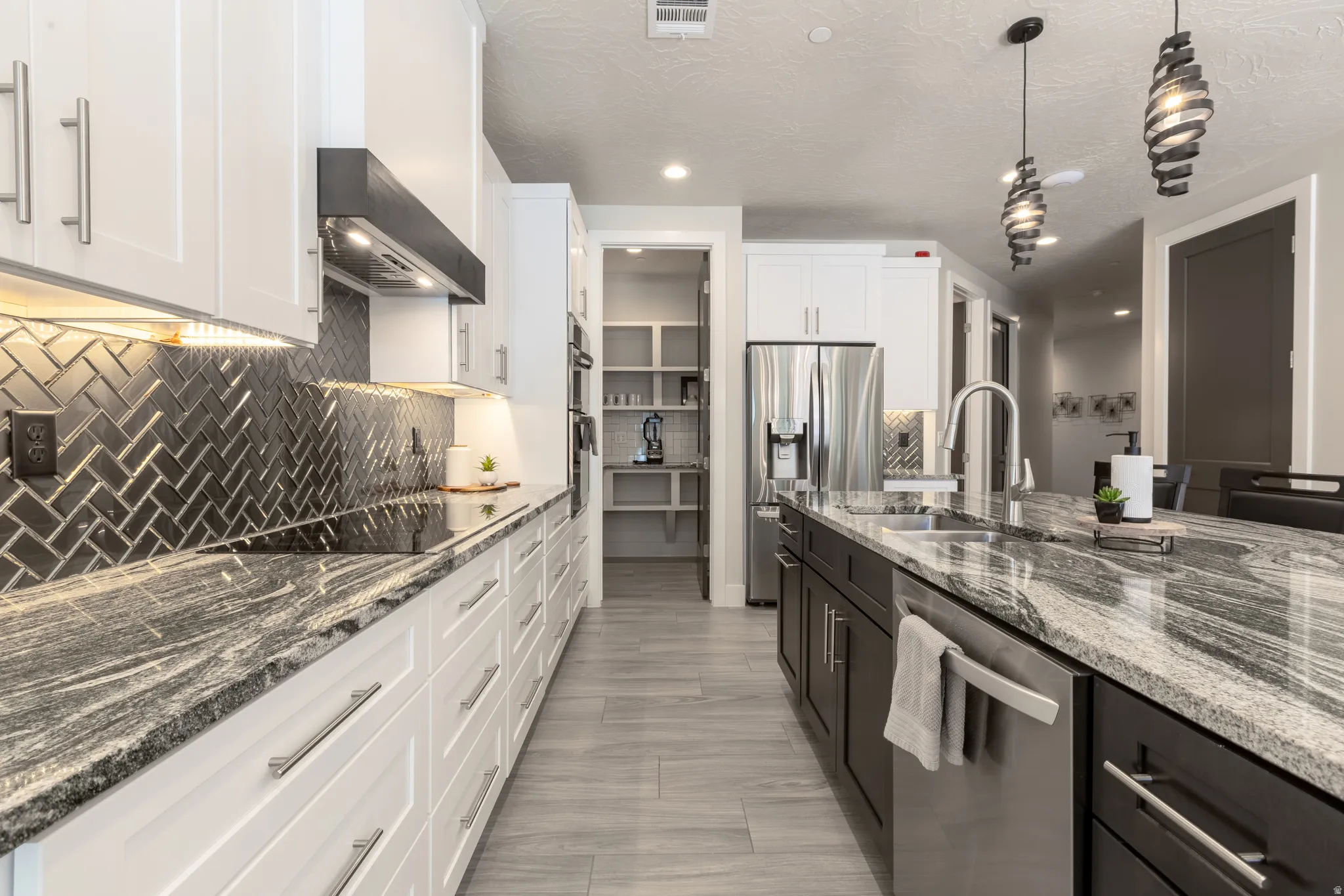 Contemporary kitchen featuring a large island with an undermount sink, a stainless steel appliance suite, and wood-finish flooring
